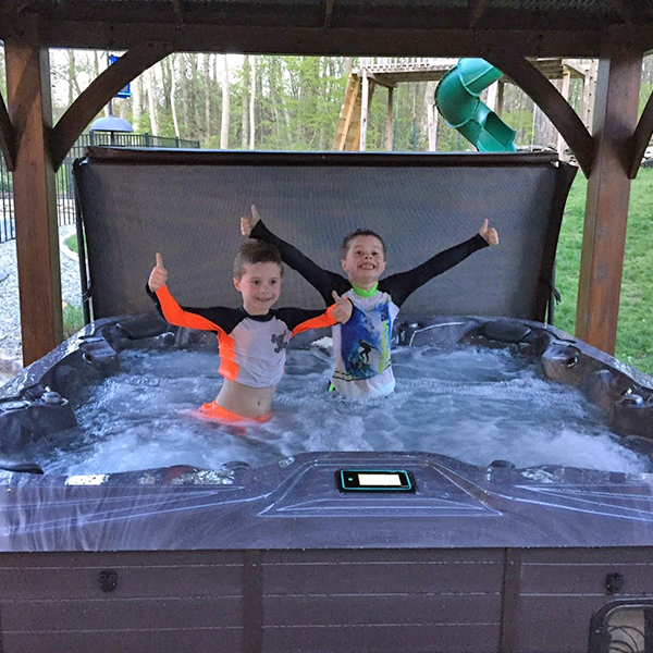 two kids giving a thumbs up in a hot tub