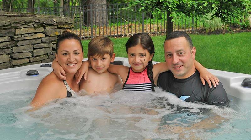 family smiling in a hot tub